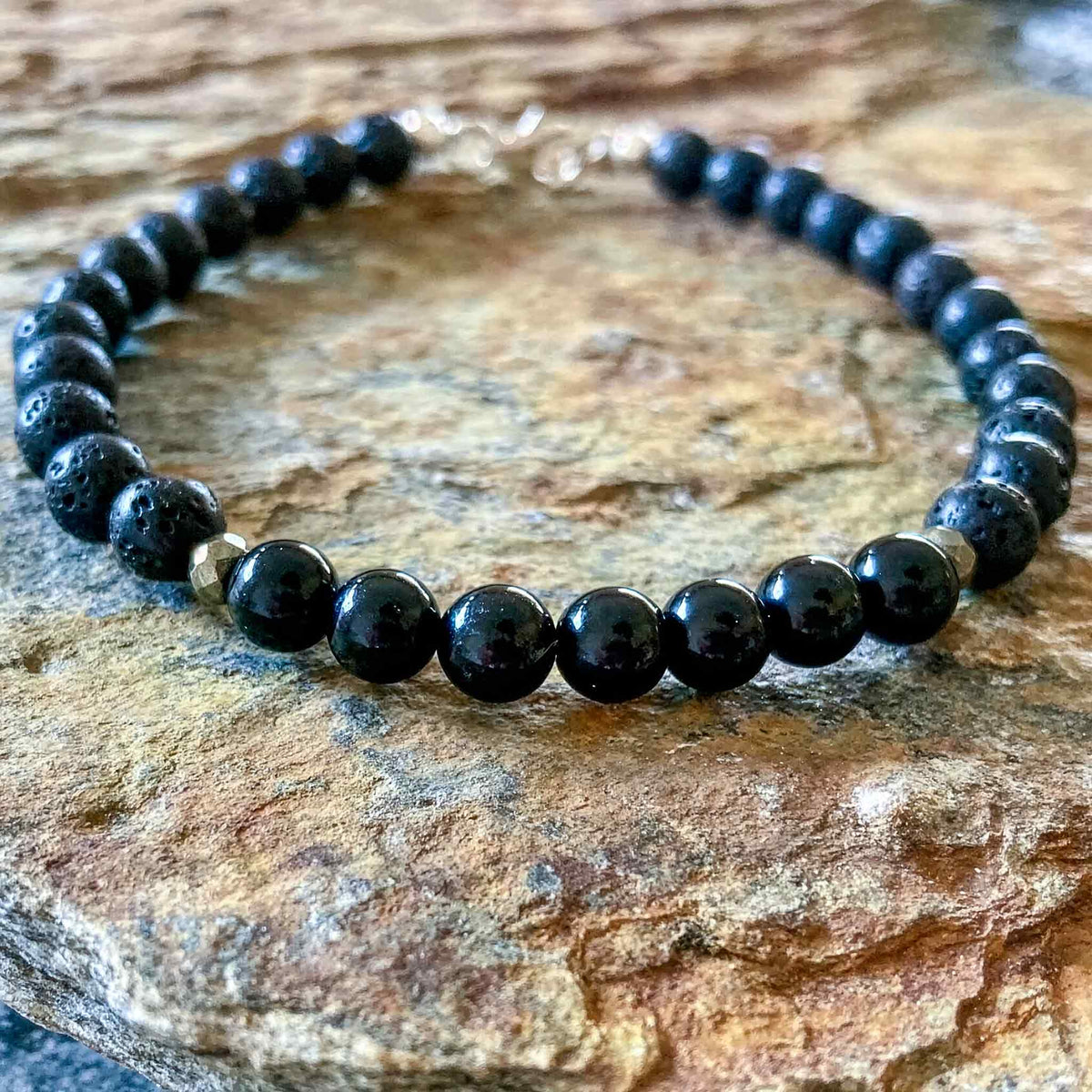 Inner Strength men's bracelet: black tourmaline with lava stone and pyrite beads, on rock