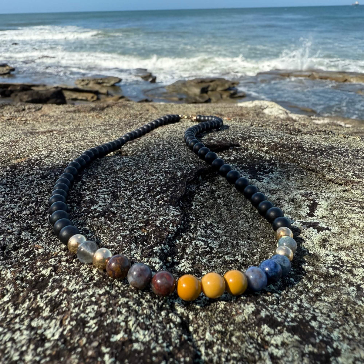 Phoenix Rising necklace's mookaite and dumortierite beads, on a rock shelf