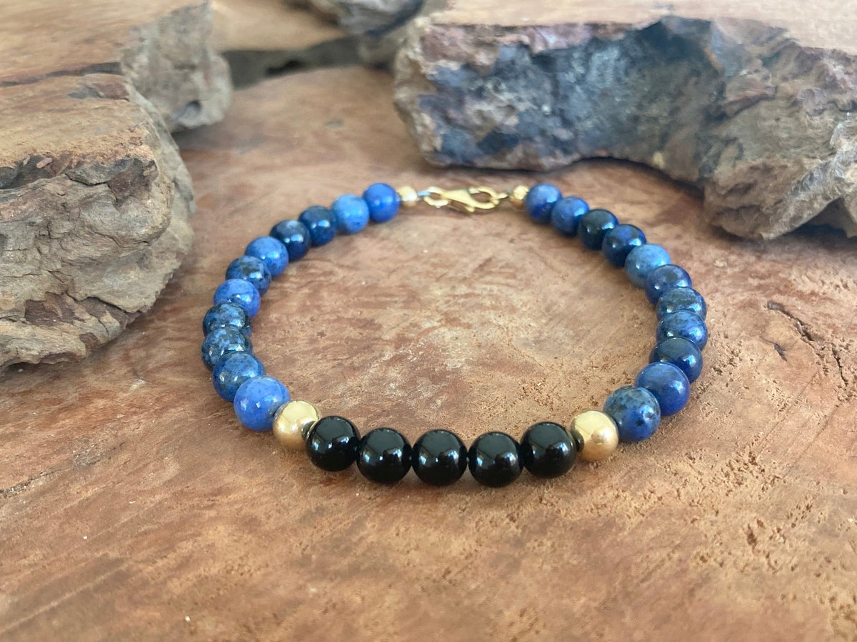 The Architect dumortierite and onyx bracelet on wood with rocks behind