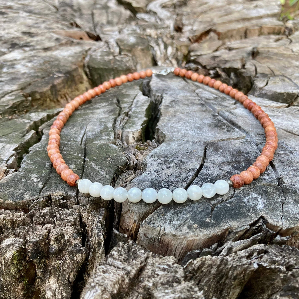 Balance necklace laid in a circle on a tree stump