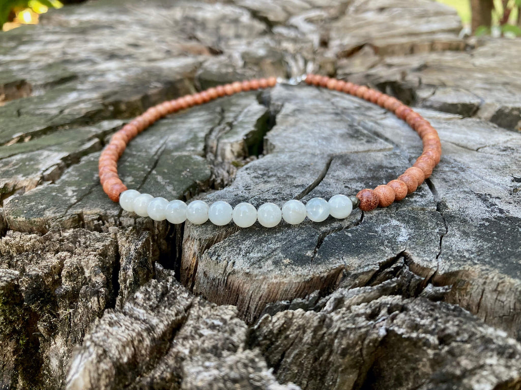 Close-up of the Balance necklace's moonstone beads on weathered wood
