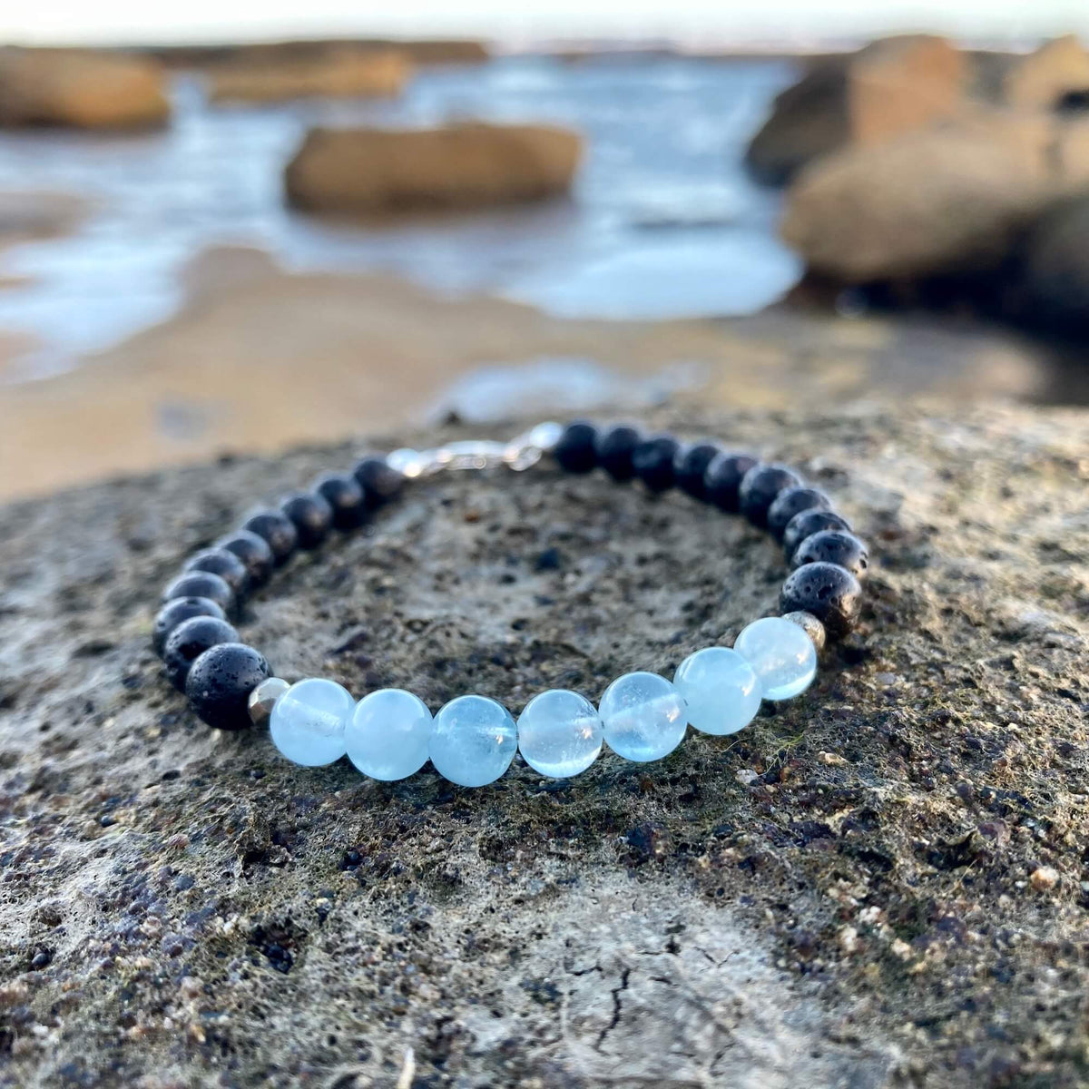 Close-up of the Courage bracelet's aquamarine beads on volcanic rock