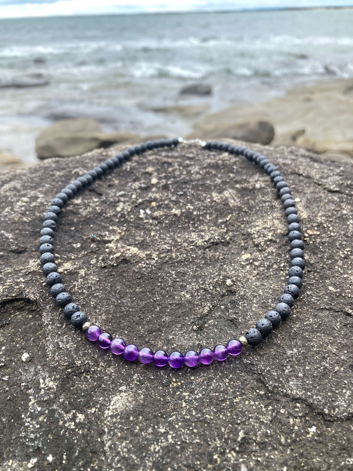 Close-up of the Zen necklace's purple amethyst beads on stone