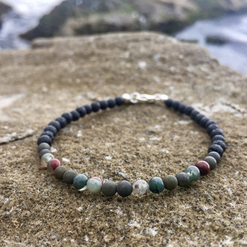 Conviction men's bracelet: bloodstone and pyrite beads on sandstone by the sea
