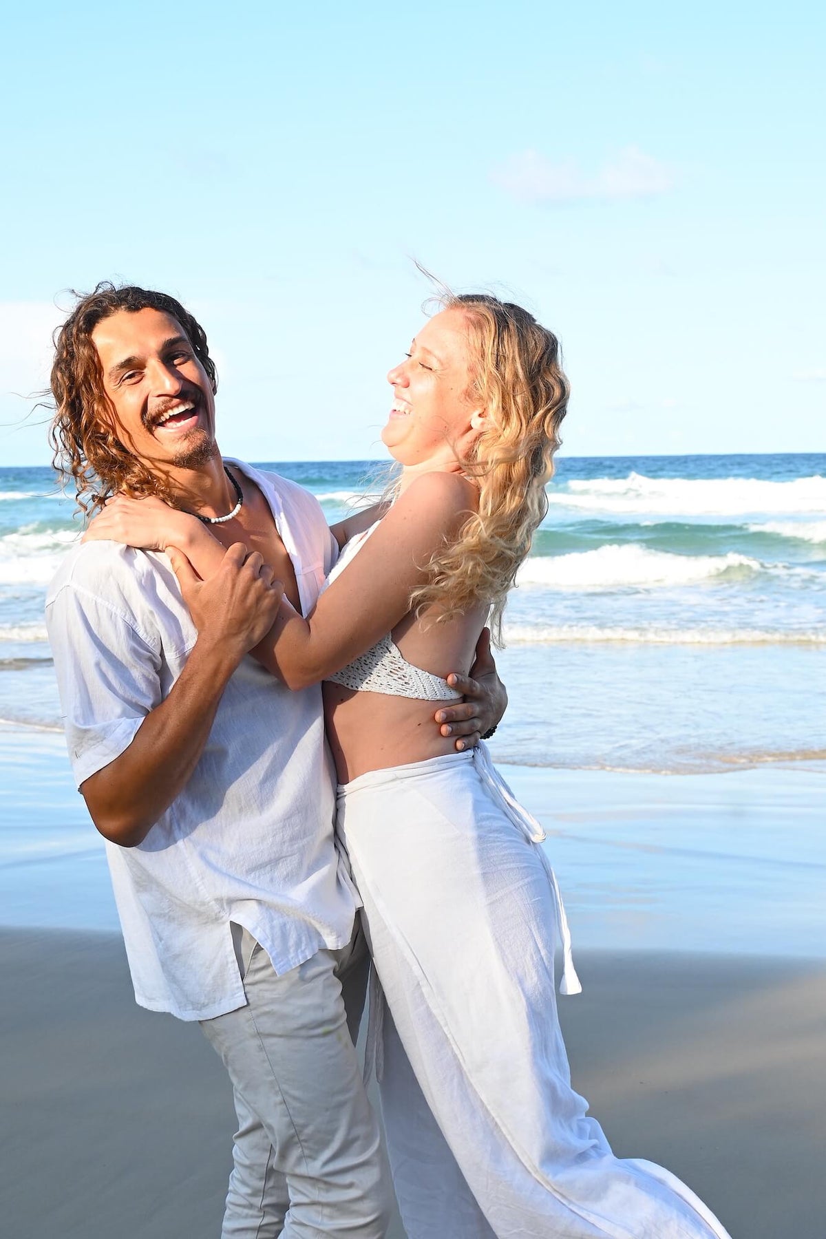 Couple laughing together by the sea, Courage necklace on him