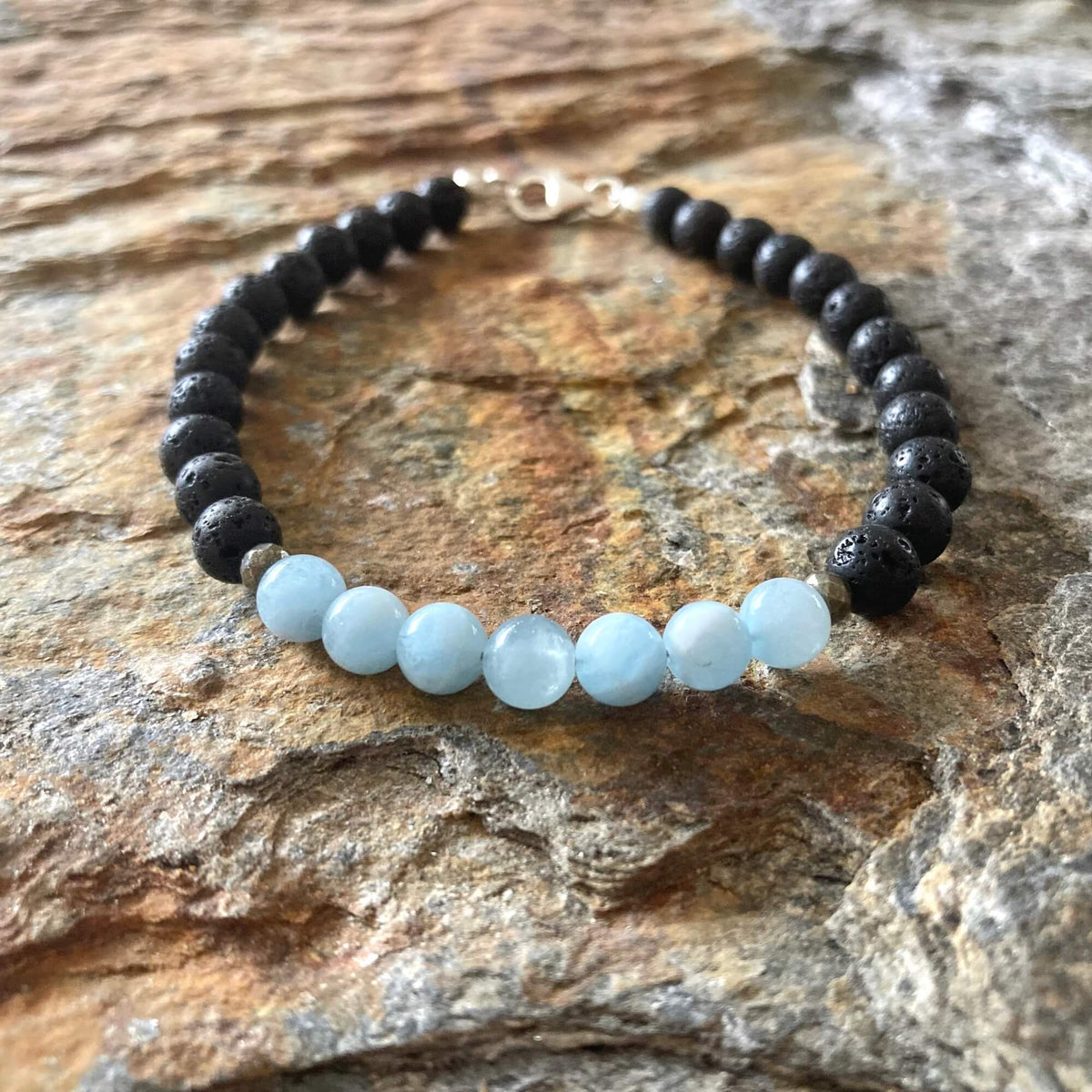 Courage bracelet from above on sandstone, sterling silver clasp at the top
