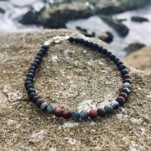 Drive men's bracelet: red tiger's eye and grey larvikite beads, on sandstone by the sea