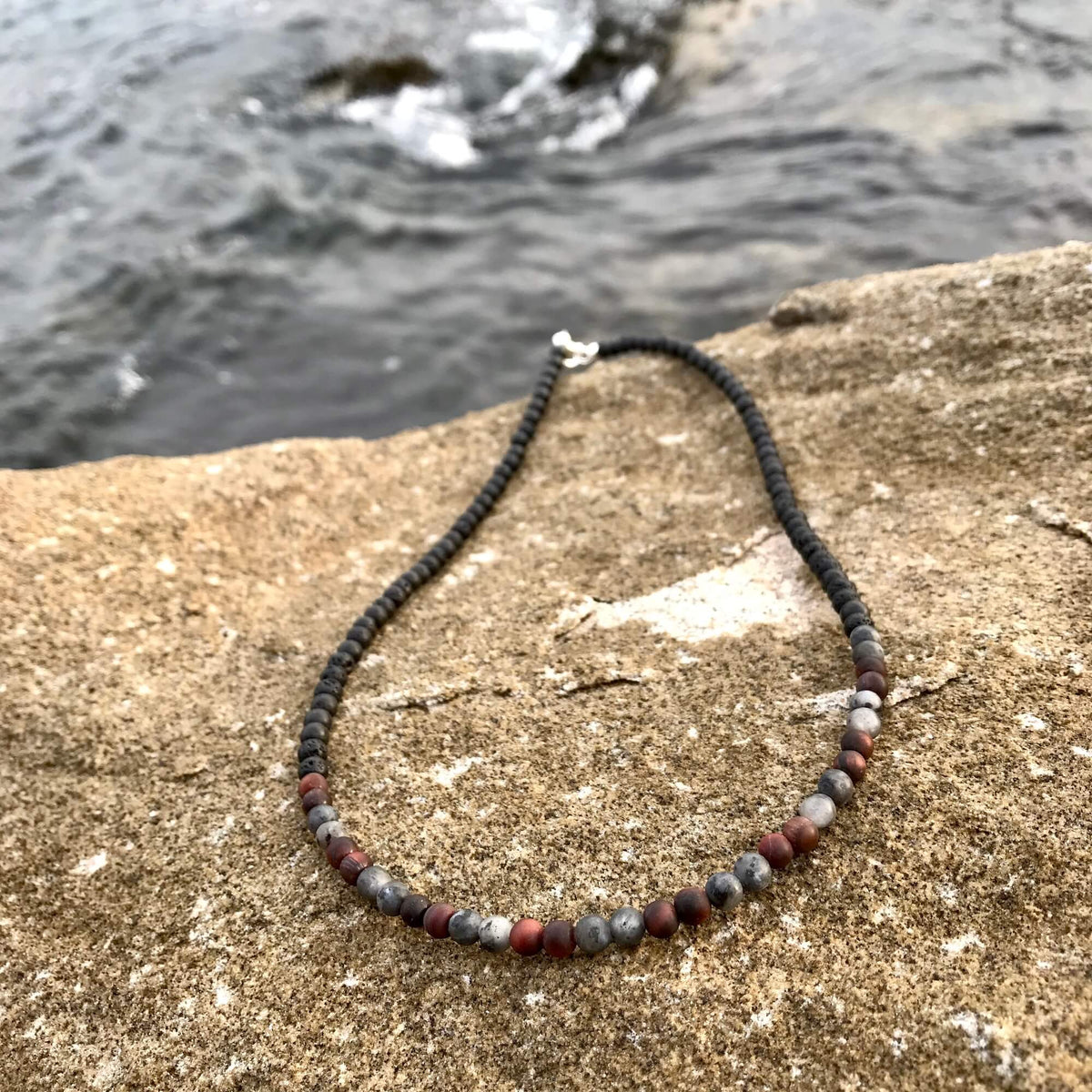 Drive necklace on rock with the ocean behind