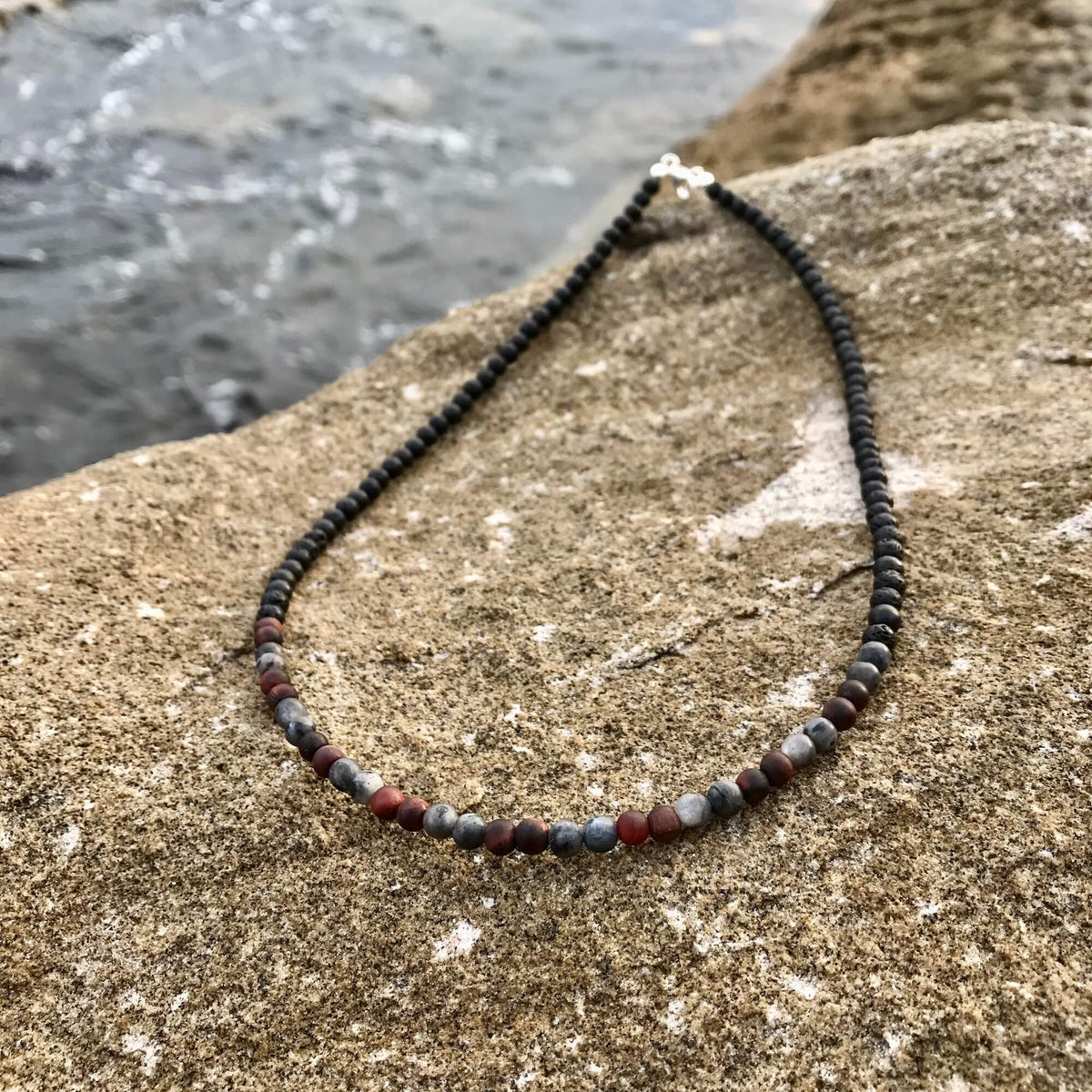 Drive red tiger's eye and larvikite necklace on coastal rock