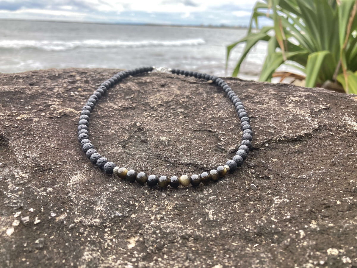 Facing Fears necklace on a coastal rock with grasses behind