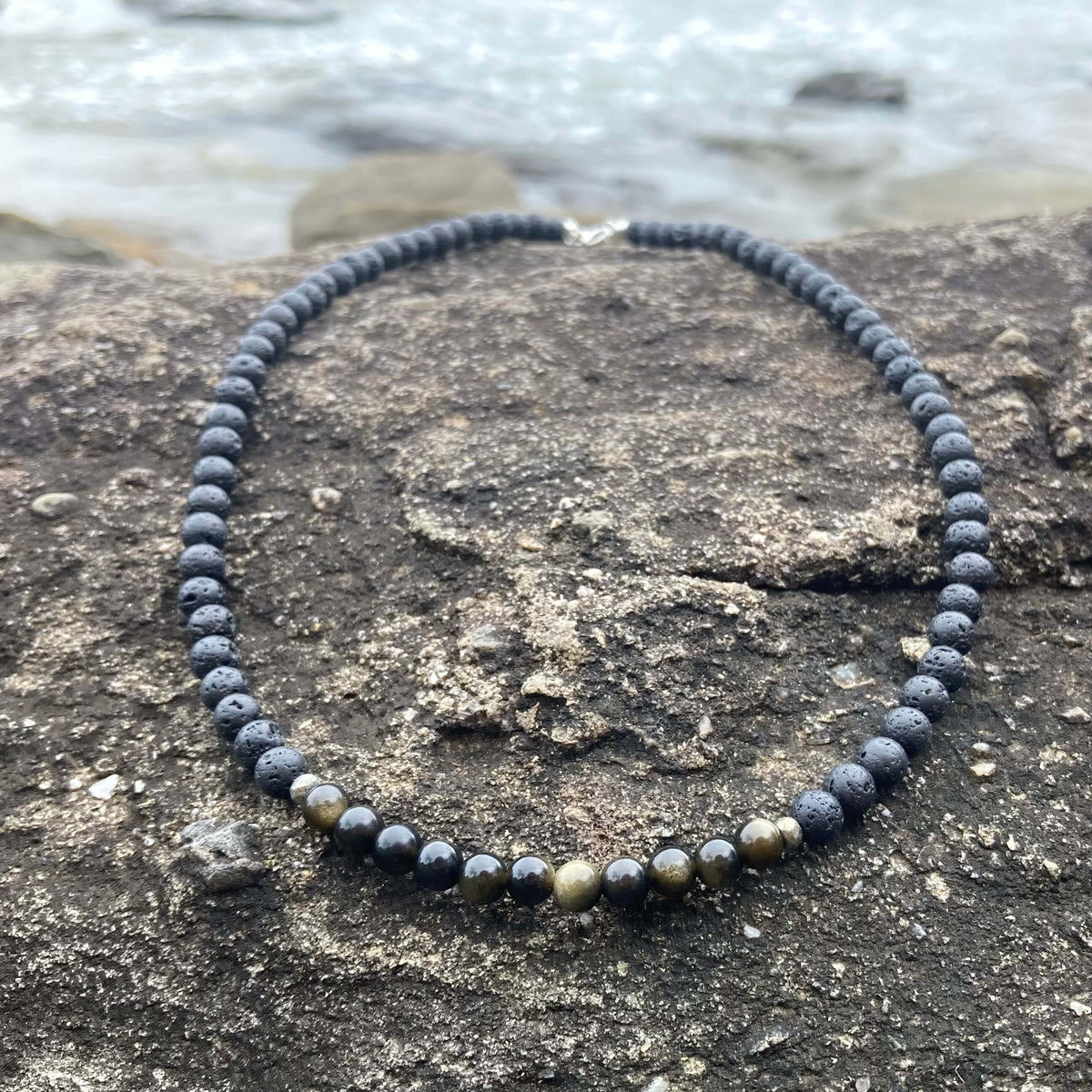 Facing Fears necklace on rock, sterling silver clasp at the top