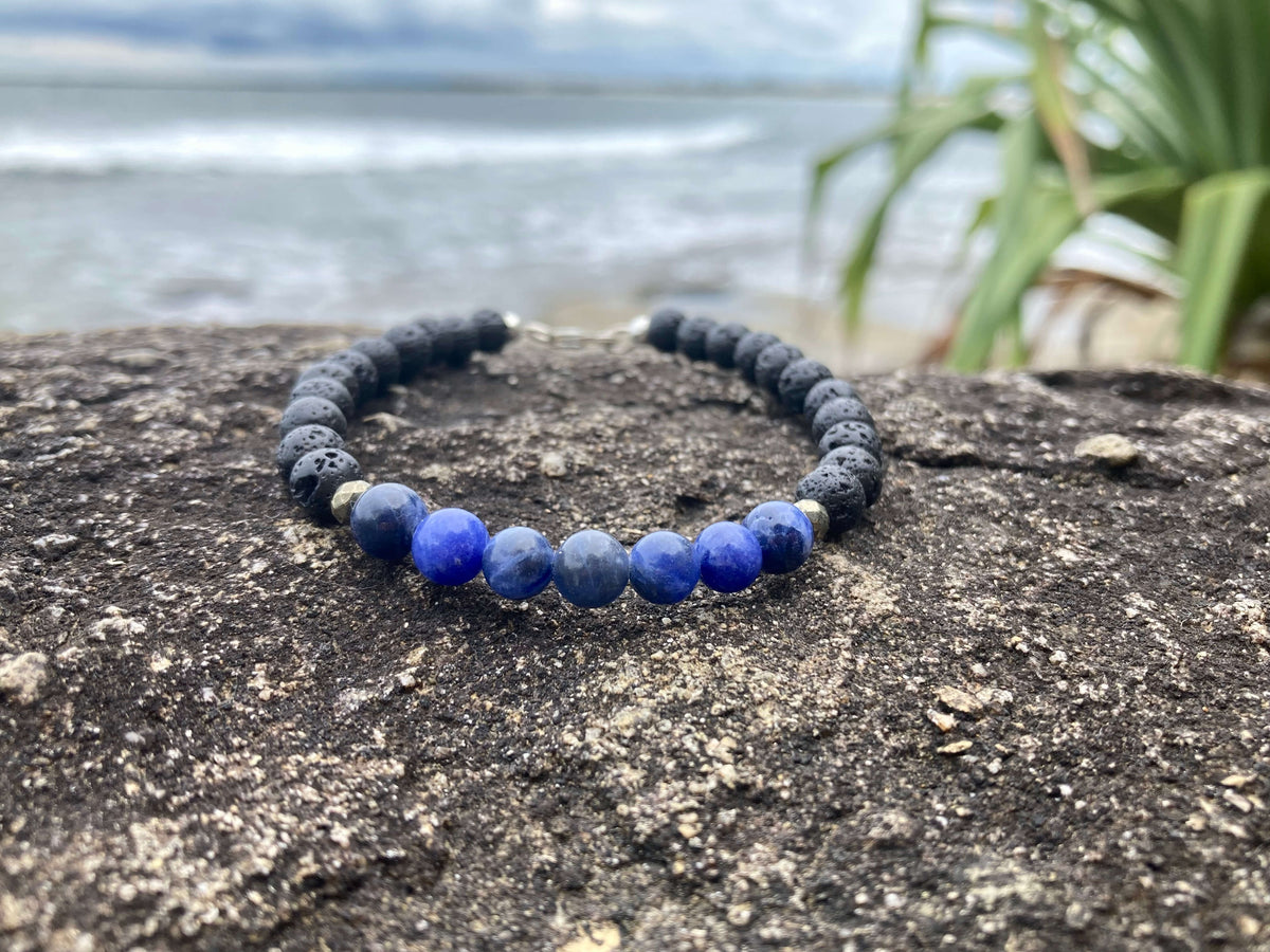 Focus bracelet on a rock by the sea with palm leaves behind
