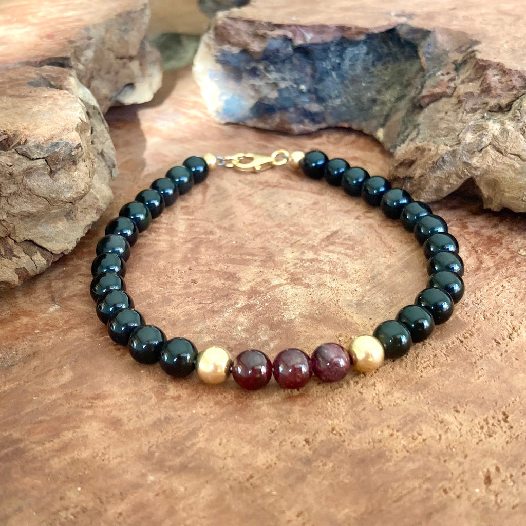Close-up of garnet and black obsidian beads on men's protective bracelet