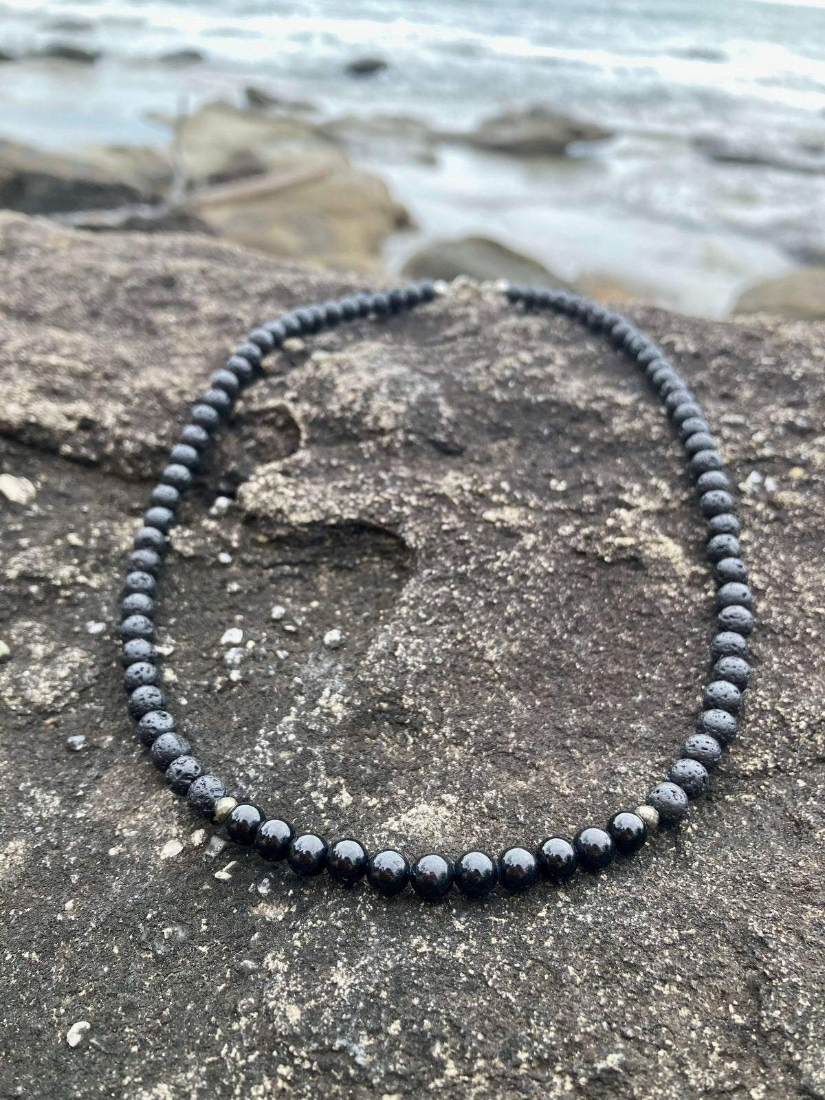 Inner Strength necklace on coastal rock, seen from further back
