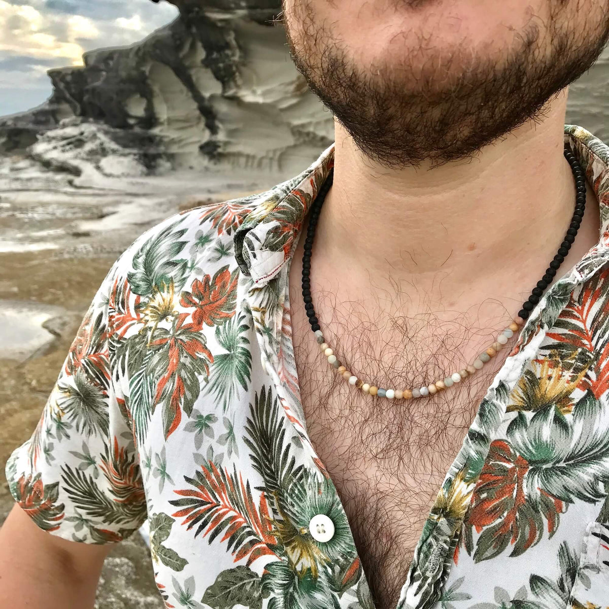 Man by the water wearing the Vitality sunstone and amazonite necklace