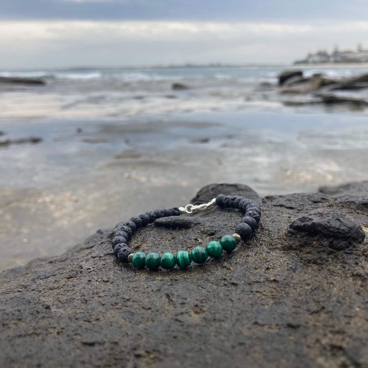 Manifestation bracelet on a coastal rock with the ocean behind