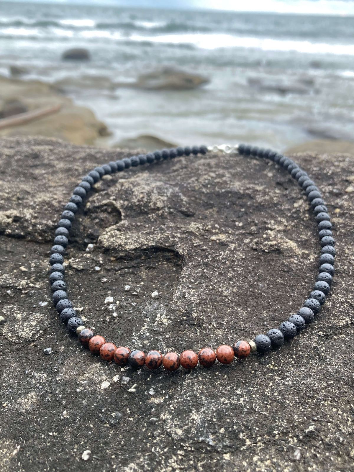 Red obsidian section of the Self-Acceptance necklace on dark rock