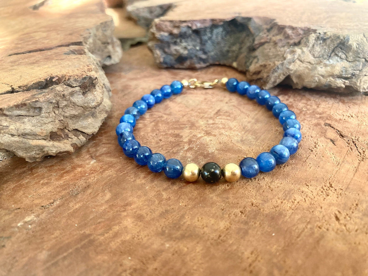 The Seeker bracelet on a wooden slab beside a rock, seen from further back