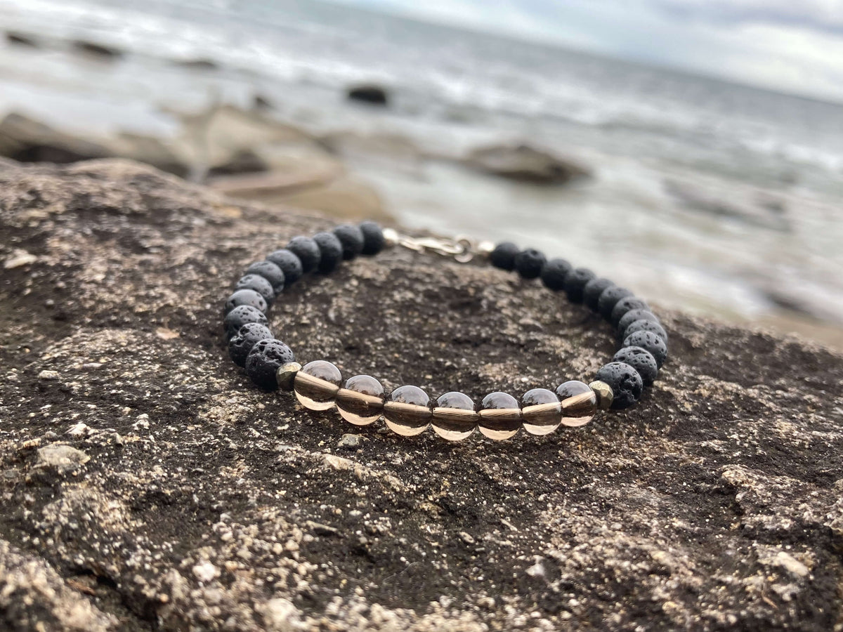 Self-Assurance smoky quartz bracelet on a rock ledge by the water