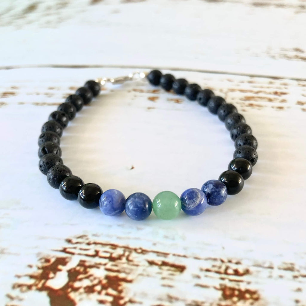 Stillness bracelet's sodalite and green aventurine beads framed by black tourmaline, on white wood