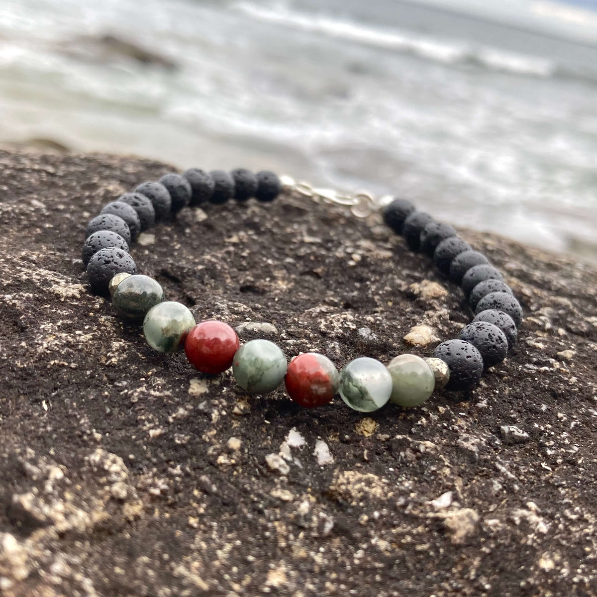 Strength bracelet on dark rock with the shoreline blurred behind