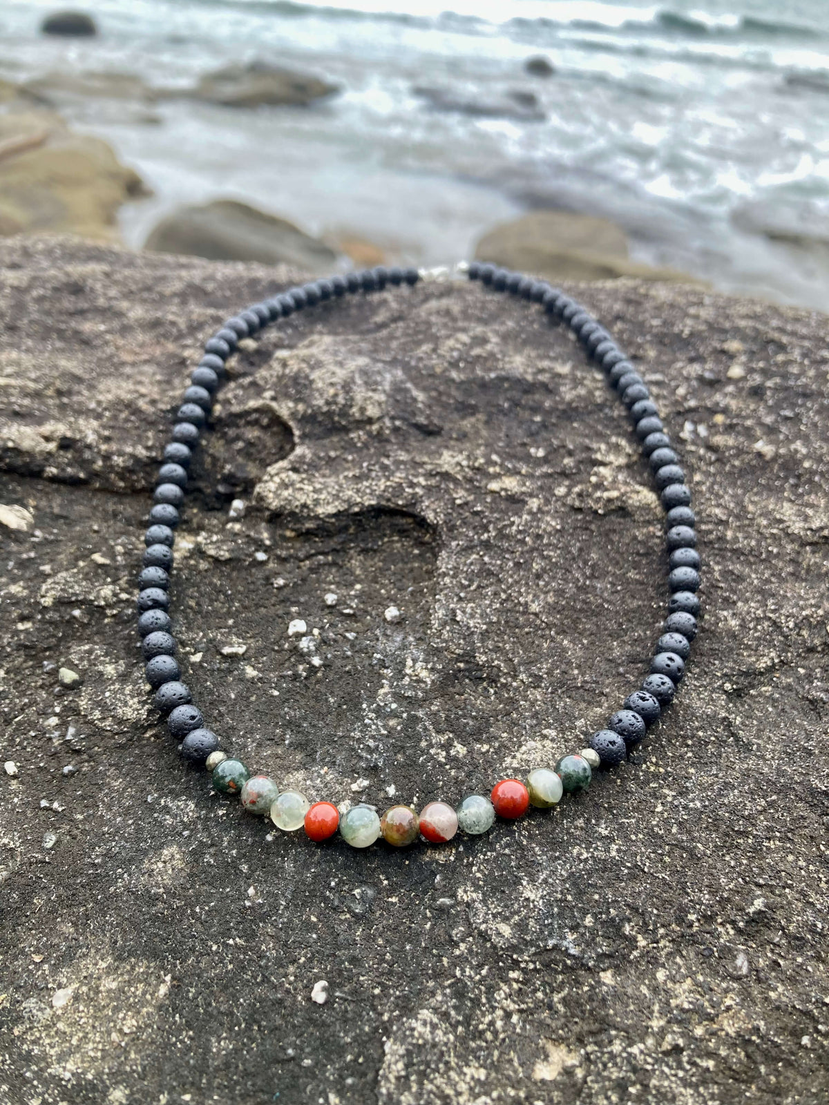 Strength necklace on a rock with waves behind