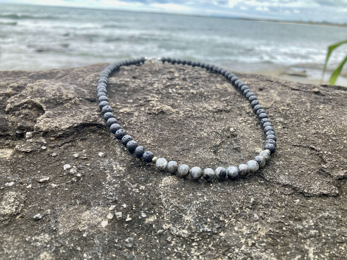 Transformation necklace on a flat rock with grasses behind