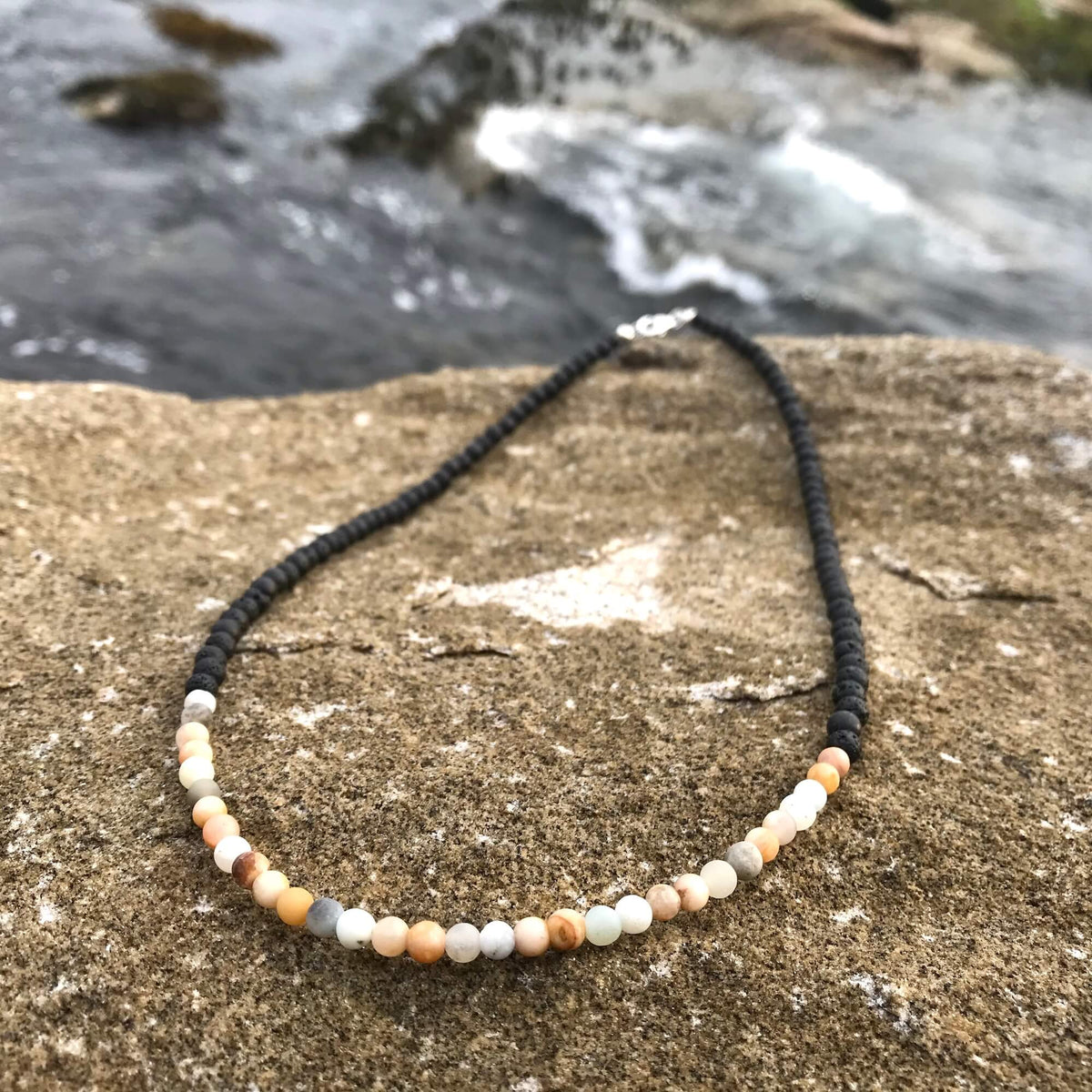Vitality necklace's sunstone and amazonite section on a sandstone rock