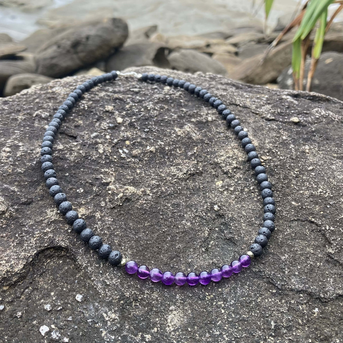 Zen necklace on coastal rock with beach stones behind