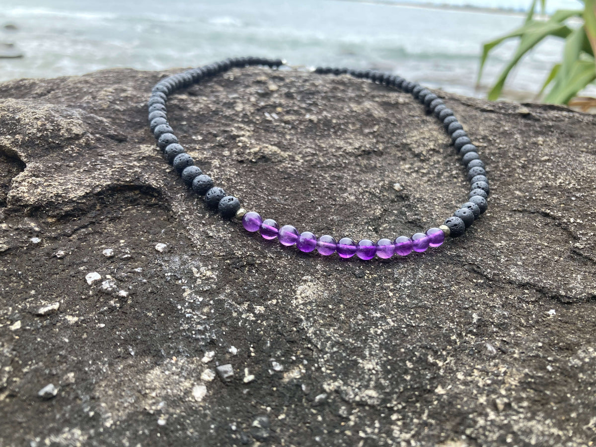 Zen necklace on a rock with grasses behind, amethyst in focus